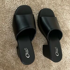 Black platformed heels, open in the front. Very chic and elegant. Never worn.